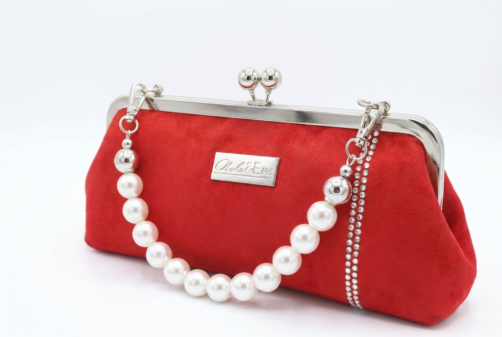 A red velvet kiss-lock clutch purse with a silver-tone metal frame, adorned with a white pearl bead chain and a silver-tone brand plaque that reads 'Nola & Eve.